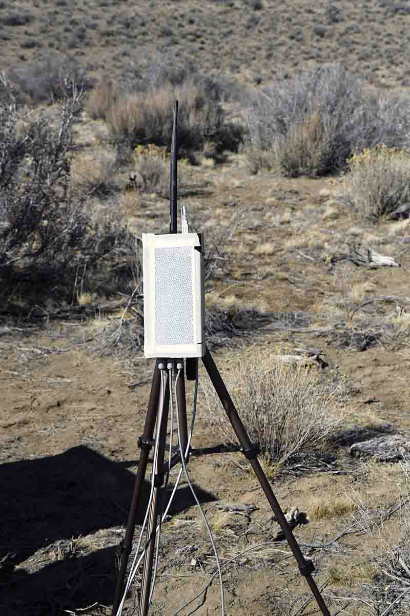 A System 89 radio with laser reflective paper taped to the face. The flexible rod extending upward is the antenna. This radio can be interchanged with the radio at the firing point, communicating data with each other.